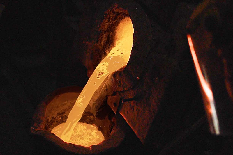 The picture shows a close-up view of molten bronze metal flowing out of a smelting furnace, from which the Sri Chinmoy bronze sculpture Compassion is being cast.