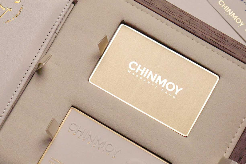 Gold metal Chinmoy warranty card on the luxury box tray