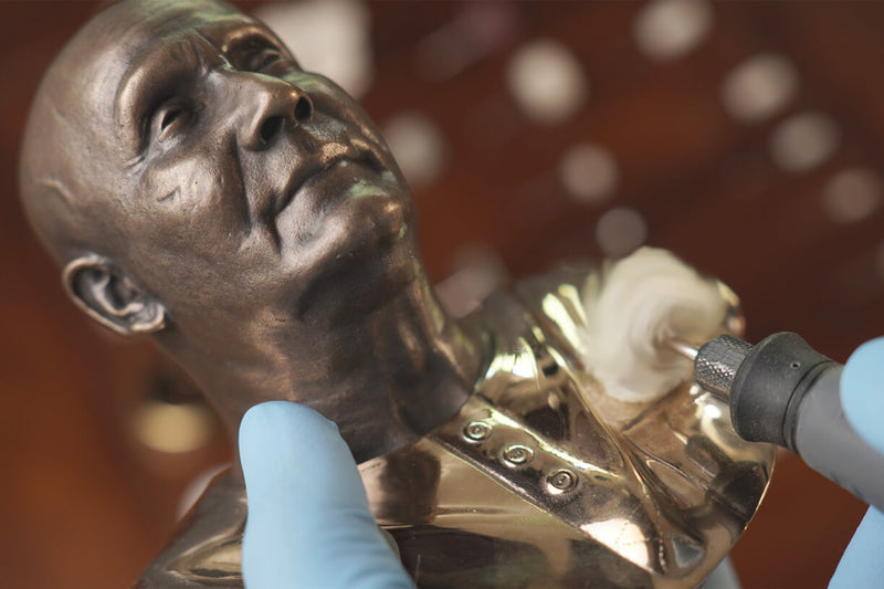 In the photo, you can see up close how the master polisher is polishing the bronze sculpture's cloth to a mirror-bright golden surface using a polishing tool..