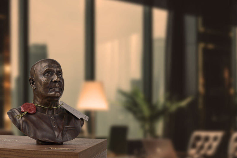 A bronze statue of Sri Chinmoy is an inspiring work of art. The statue has recently been unraveled, as you can see the original red wax seal on a gold cord attached to the statue. The inspirational artwork is displayed on a wooden box that serves as its packaging in a luxury office in a Manhattan skyscraper.